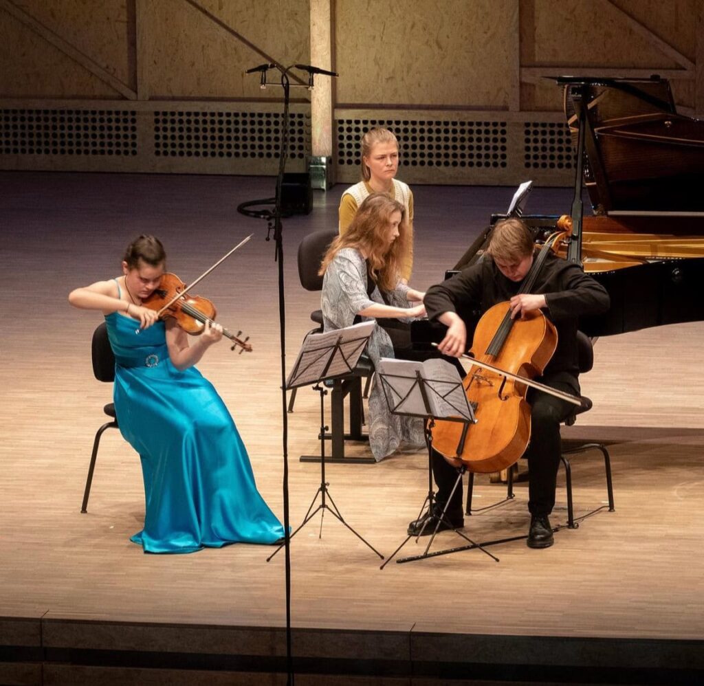 Alice Power spelar på en scen tillsammans med en cellist och en violinist