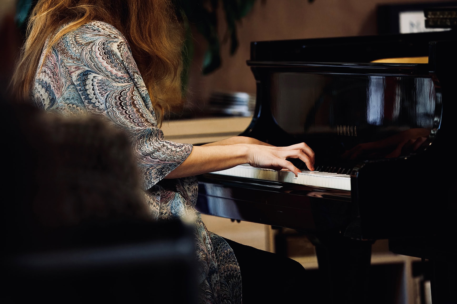 Alice is playing the grand piano and the image focuses on her hands and the keys